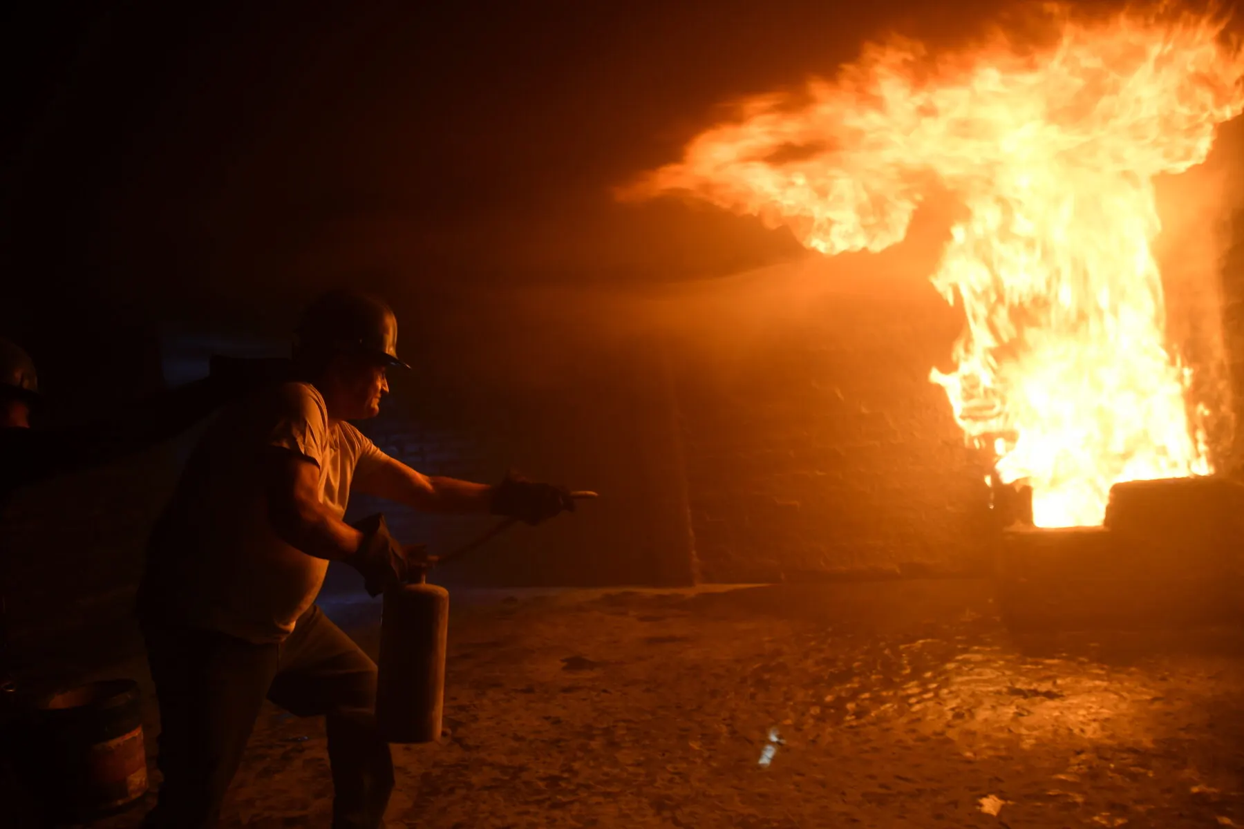 Brigadista combate una llamarada de noche en el campo de prácticas