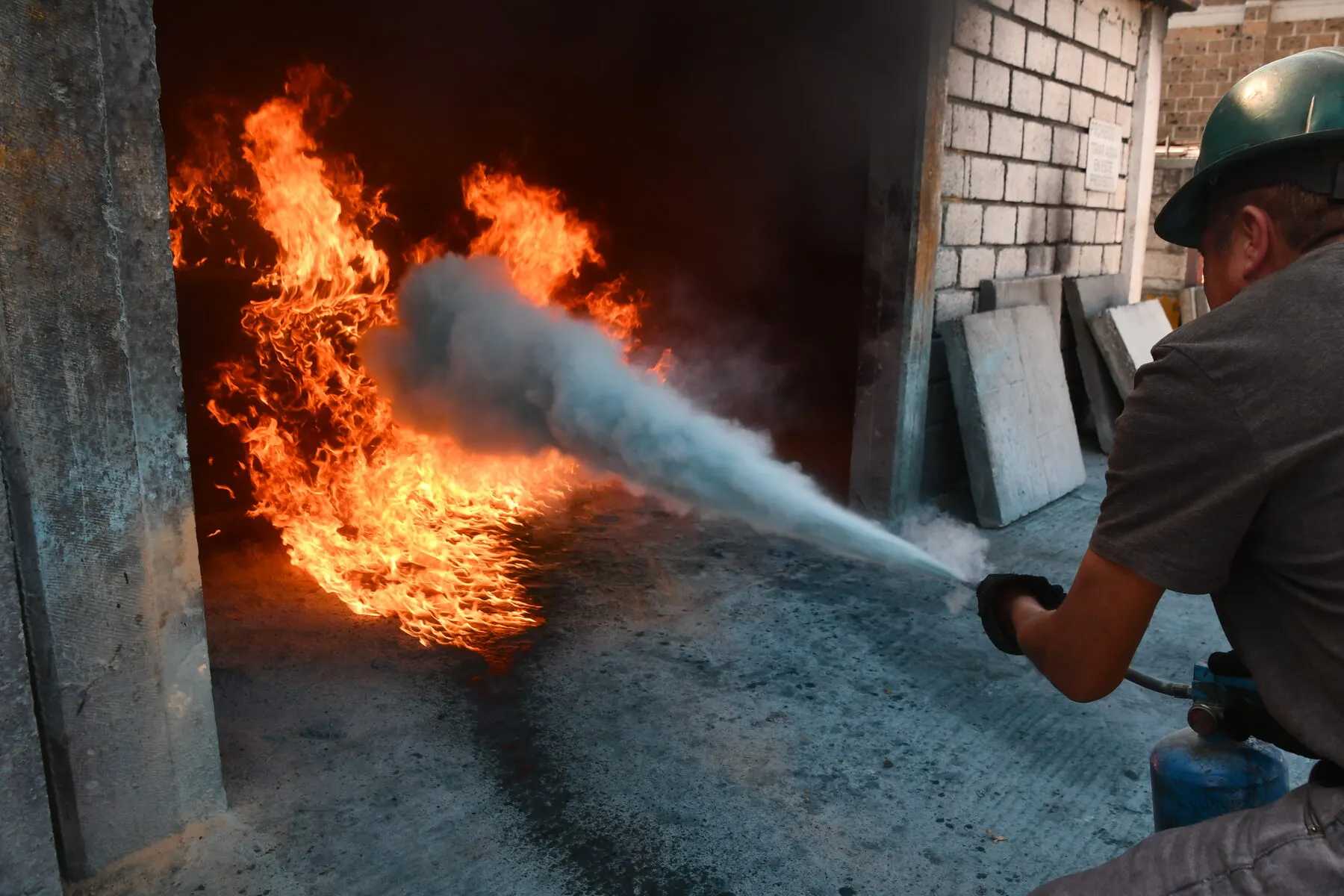 Chorro de extintor sobre el fuego dentro de un cuarto de prácticas