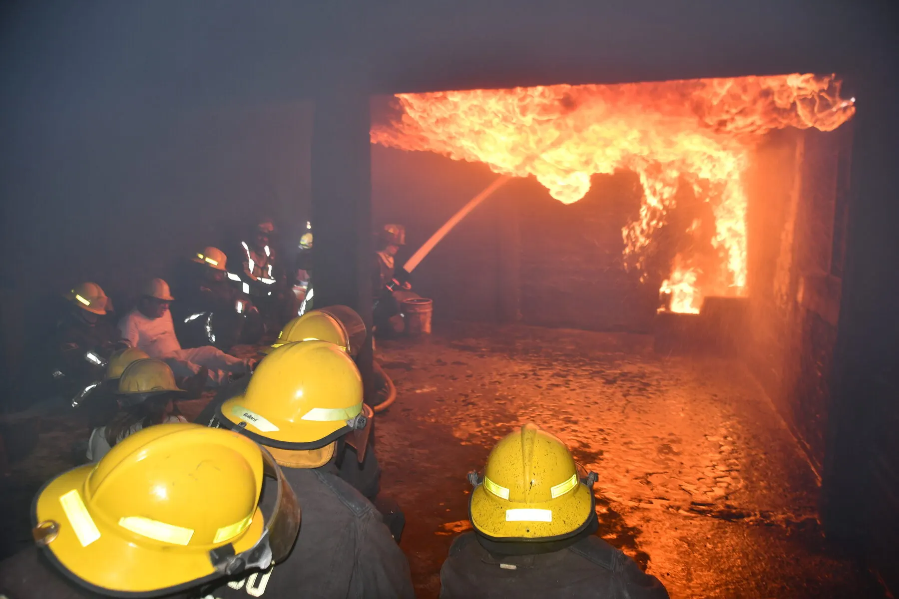 Brigadistas con casco frente a un incendio interior